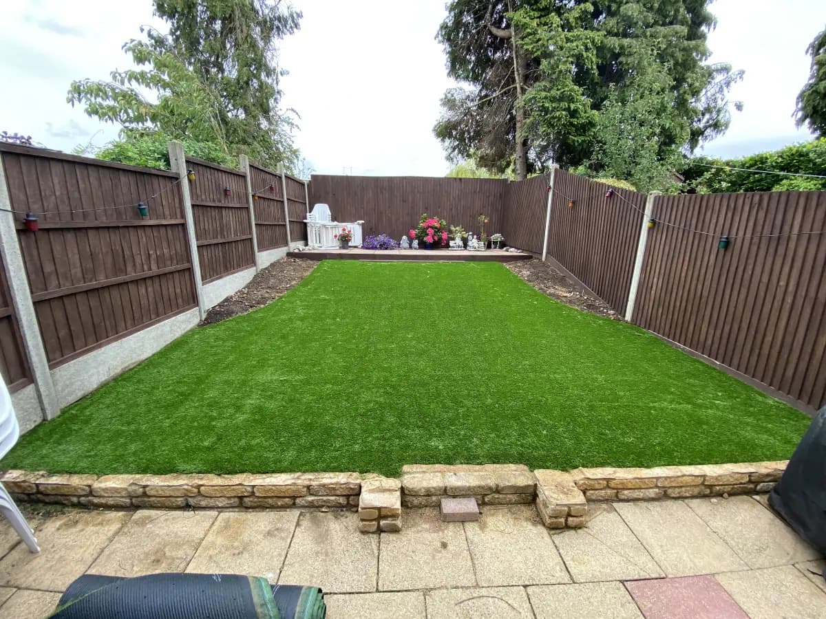 Completed back garden artificial grass installation with clean patio edging